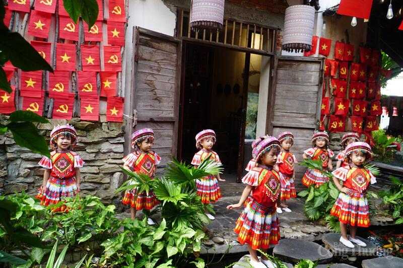 Các em nhỏ trong trang phục thổ cẩm chụp ảnh với cờ đỏ sao vàng