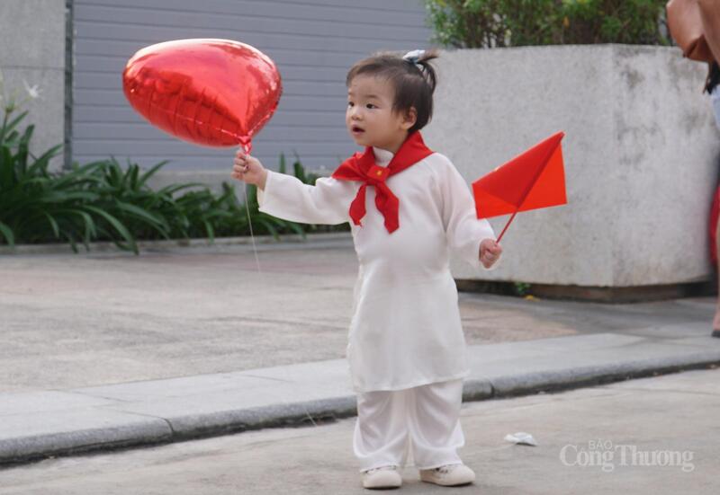 Các em nhỏ được bố mẹ diện áo dài, khăn choàng đỏ và cờ đỏ sao vàng trong ngày vui của đất nước