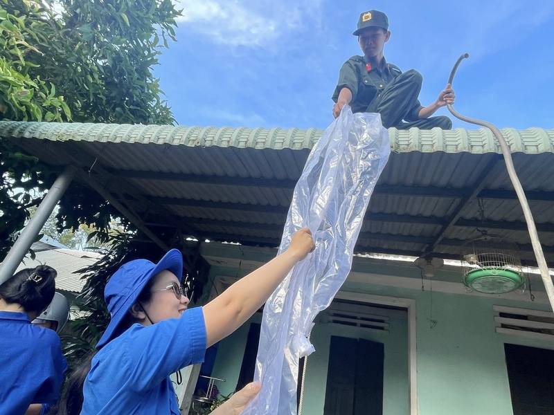 Các chiến sĩ của Đồn Biên phòng Nhơn Châu phối hợp với Đội Thanh niên xung kích xã Nhơn Châu hỗ trợ người dân gia cố nhà cửa.