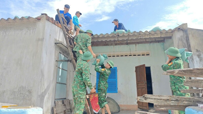 Các chiến sĩ Đồn Biên phòng Nhơn Châu hỗ trợ người dân gia cố mái nhà, chằng chống nhà cửa.
