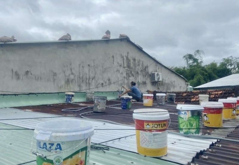 Người dân gia cố mái nhà bằng thùng sơn cũ.