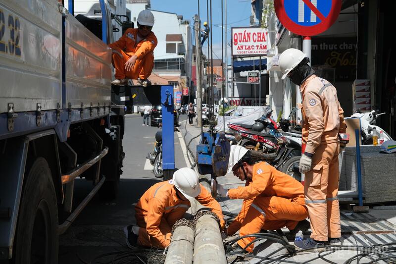 Cán bộ điện lực hỗ trợ đơn vị thi công hạ và di dời trụ điện. Ảnh: Lê Sơn